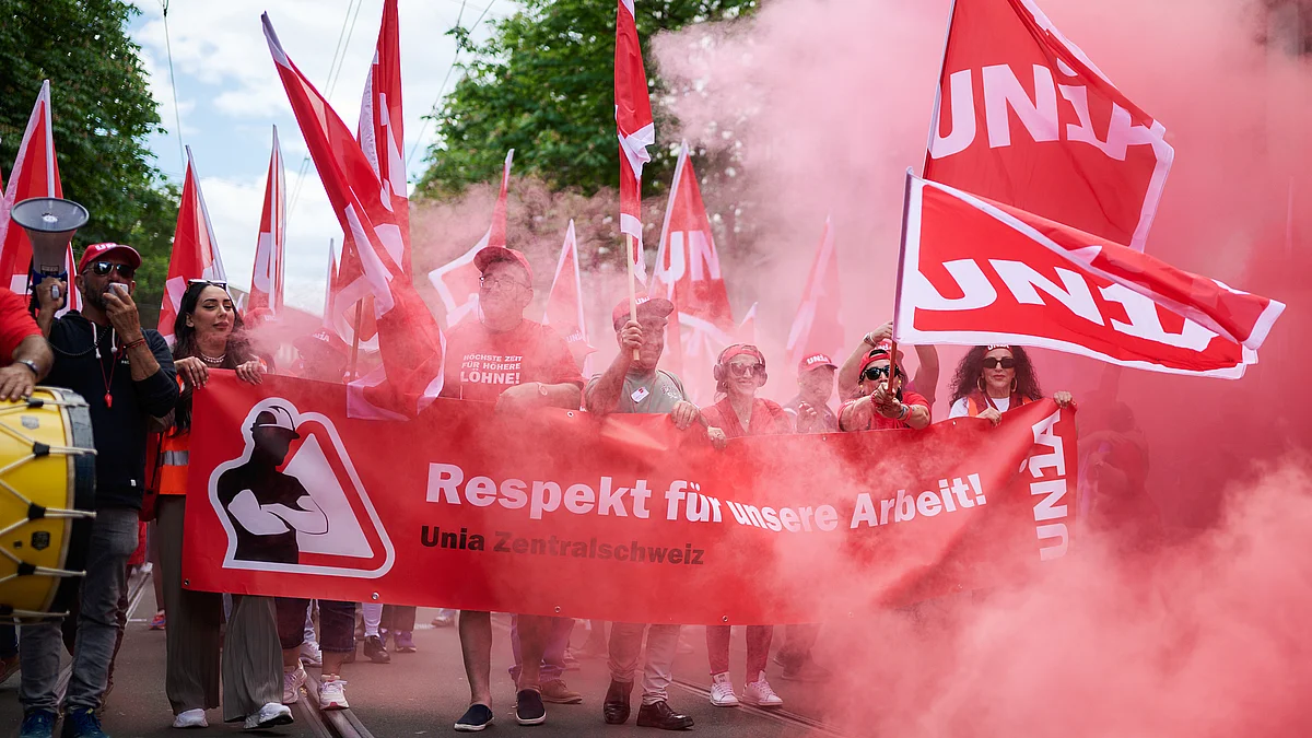 Demonstrierende der Unia Zentralschweiz mit roten Unia-Fahnen fordern auf einem Transparent mit der Aufschrift «Respekt für unsere Arbeit!» bessere Arbeitsbedingungen.